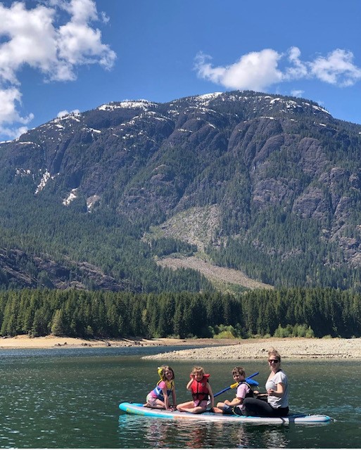 Stephanie & her children on a paddle board in a mountain bay