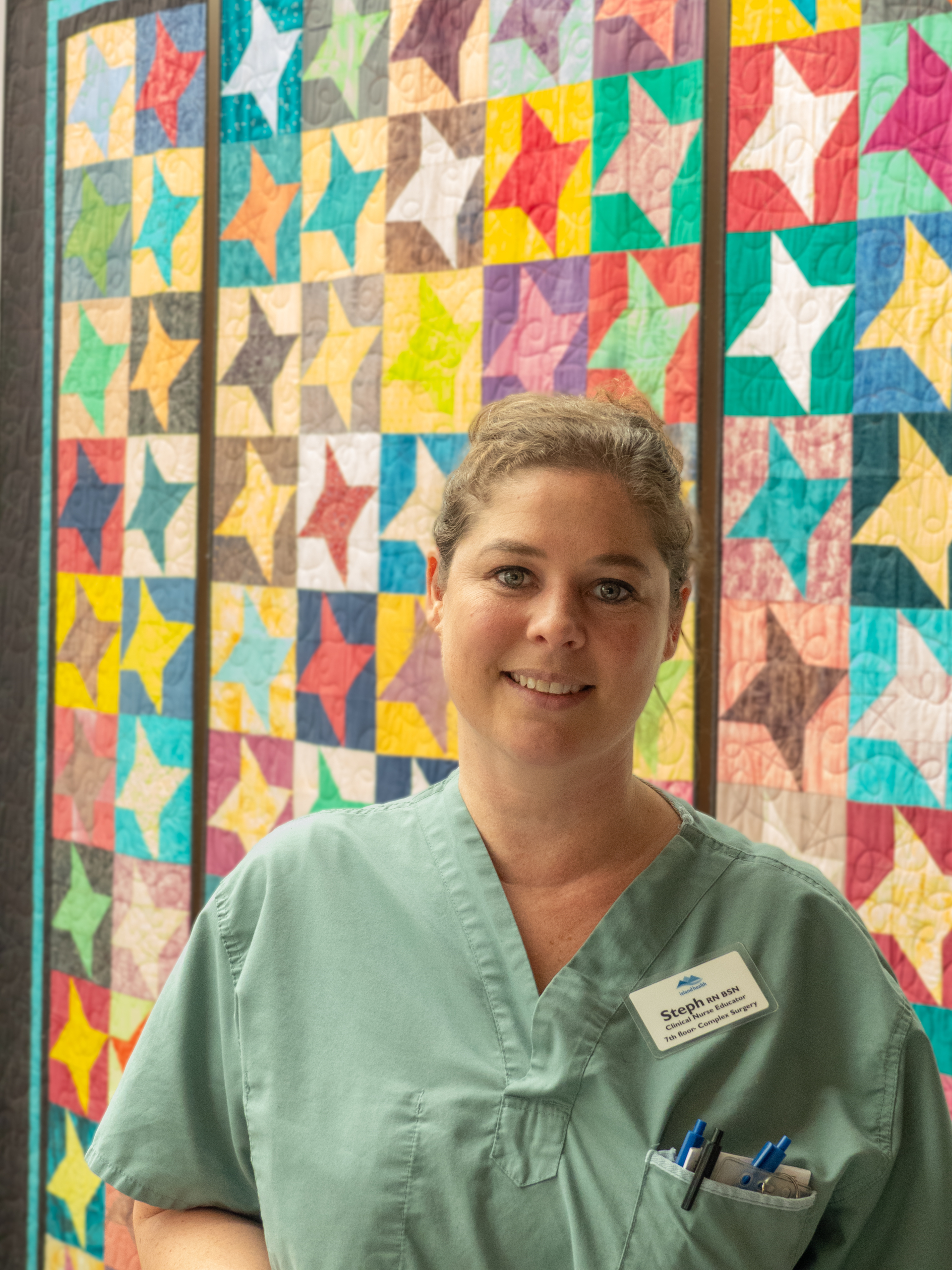 Stephanie Sprout, CNE, in front of a quilt at Royal Jubilee Hospital