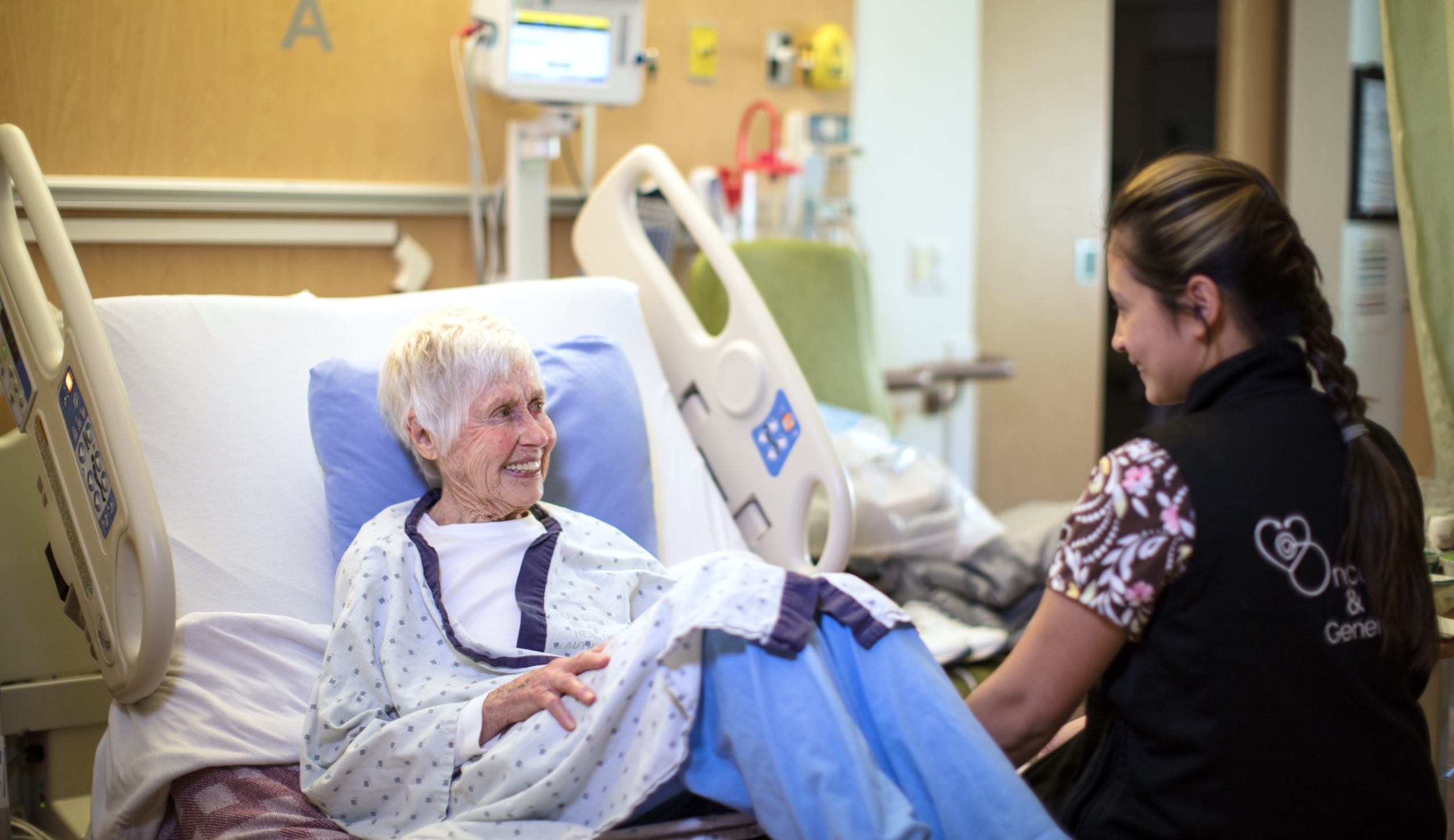 Elderly cancer patient with a nurse in a hospital room