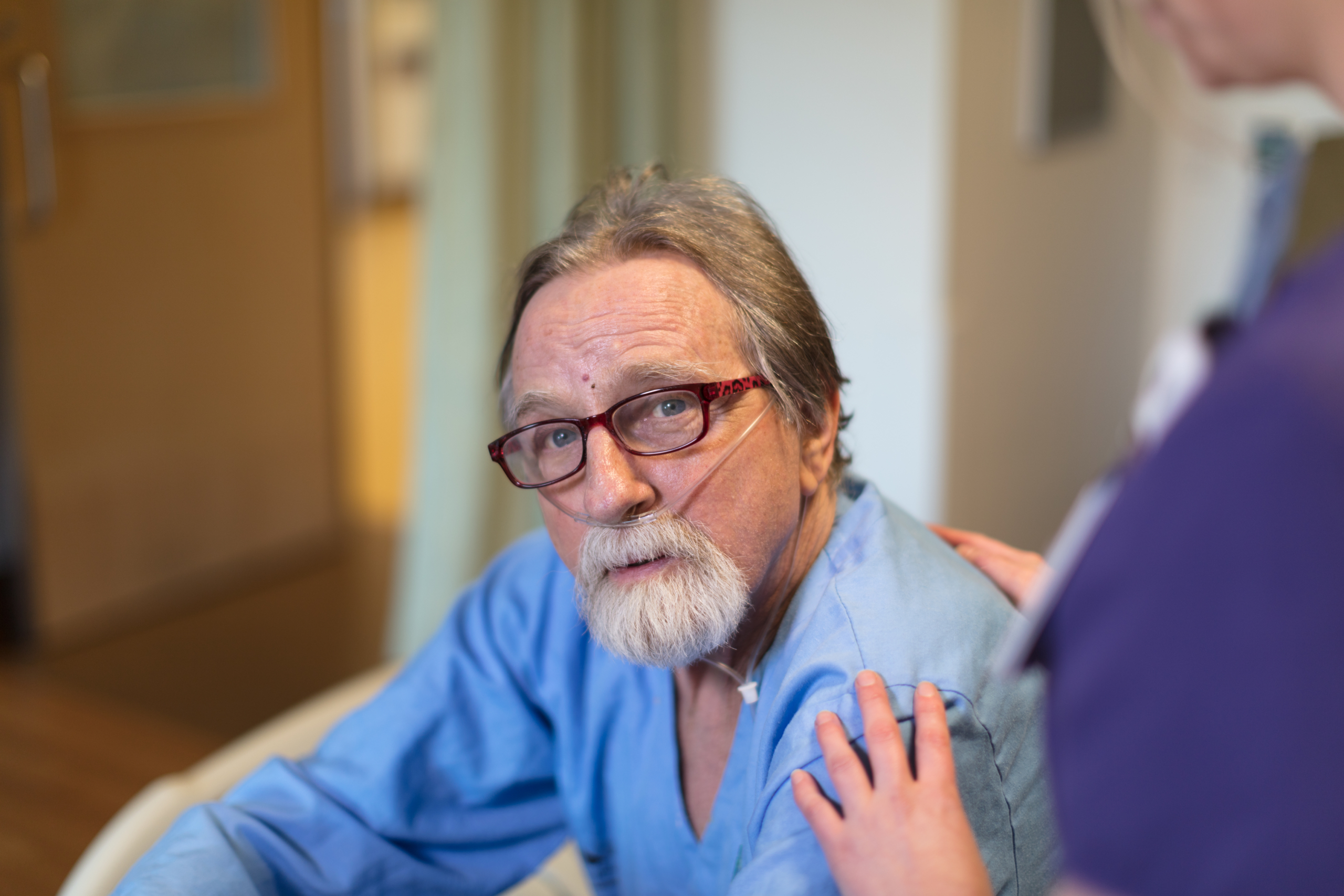 Patient looking off as a nurse pats their shoulder