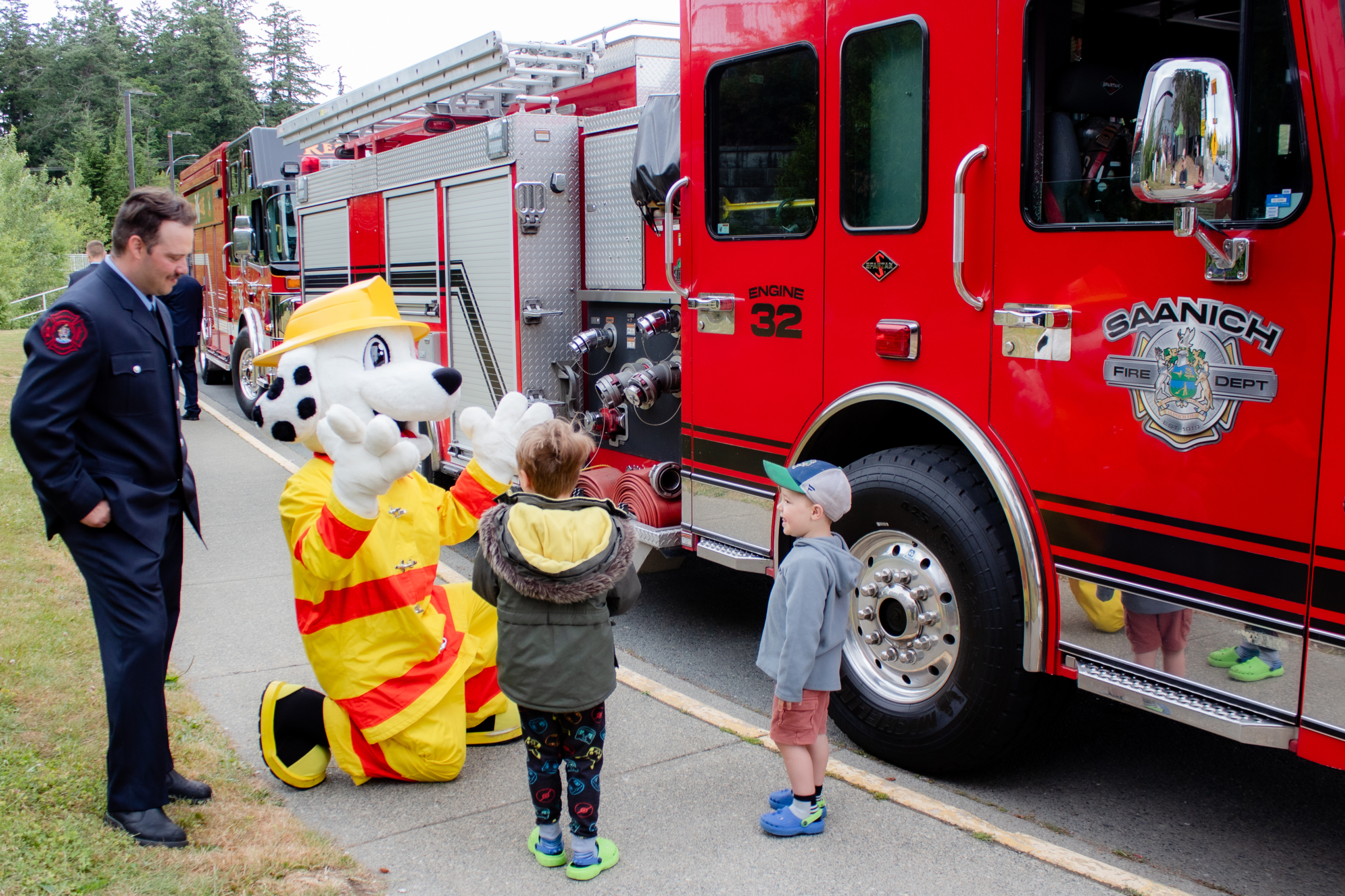 Sparky the Fire Dog shows a firetruck to former NICU pediatric patients outside of Victoria General Hospital