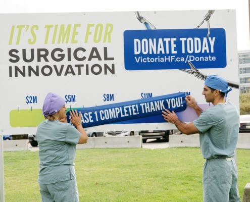 Drs. Mona Mazgani (Gynecologic Oncologist) and Sepehr Khorasani (Colorectal Surgeon) place the campaign completion decal on the Victoria Hospital Foundation's Campaign progress sign at Victoria General Hospital