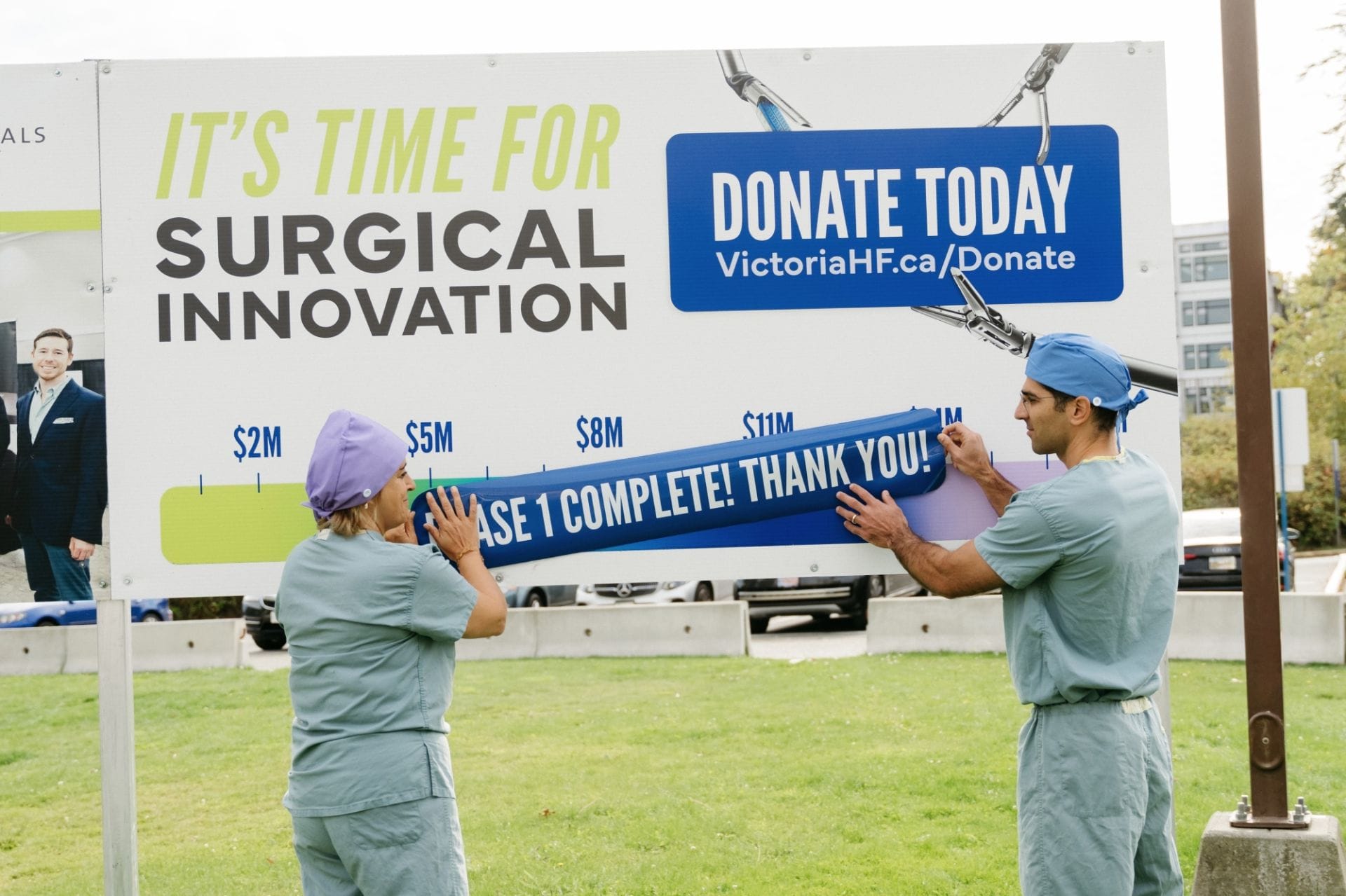 Drs. Mona Mazgani (Gynecologic Oncologist) and Sepehr Khorasani (Colorectal Surgeon) place the campaign completion decal on the Victoria Hospital Foundation's Campaign progress sign at Victoria General Hospital